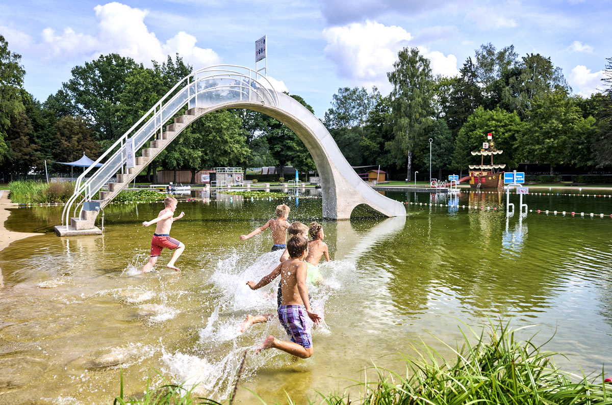Mehrere Kinder toben im See des Waldstrandbads